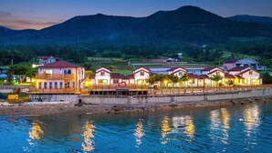 A waterfront property with multiple houses, a dock, and a mountain backdrop. - Yeosu Hi Mom Kids Family Pension Gold (Yeosu)