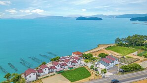 A coastal residential area with houses, a road, and a clear view of the sea. - Yeosu Hi Mom Kids Family Pension Gold (Yeosu)
