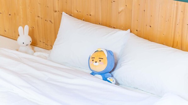 A bed with white bedding and a plush toy in a blue outfit. - Yeosu Hi Mom Kids Family Pension Gold (Yeosu)