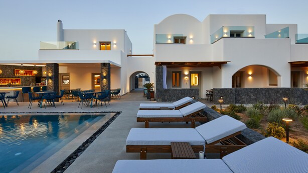 A modern resort with a pool area, lounge chairs, and a bar. - Mountain and Sea Suites (Santorini)