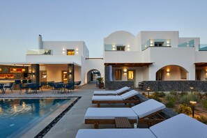 A modern resort with a pool area, lounge chairs, and a bar. - Mountain and Sea Suites (Santorini)