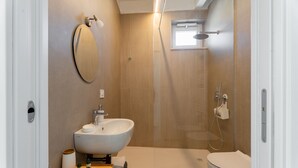 Une salle de bain moderne dotée d’un grand lavabo, de toilettes et d’un espace douche.