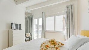 Une chambre d’hôtel avec un lit, un téléviseur posé sur une commode et une vue sur l’extérieur.
