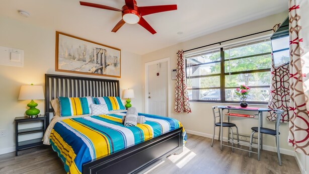 A hotel room with a bed, a desk, a chair, a ceiling fan, and a window with curtains. - 🏳️‍🌈 #1 Walk to Wilton Drive (fort lauderdale)