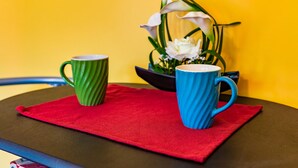 Two mugs on a table with a red cloth, a yellow wall, and a white flower arrangement in the background. - 🏳️‍🌈 #3 Walk to Wilton Drive (fort lauderdale)