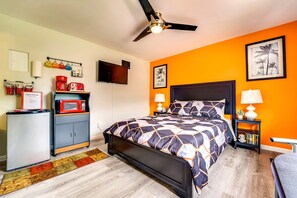 Une chambre avec un lit, un ventilateur de plafond, une télévision et un bureau avec un four à micro-ondes.