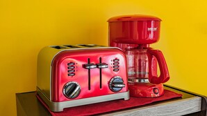 A red toaster and coffee maker on a wooden tray against a yellow background.