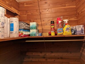 Cleanliness is maintained with a well-stocked shelf featuring paper towels, toilet paper, and cleaning products.
