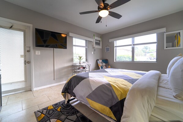Relax in a spacious bedroom with a large bed and ceiling fan, featuring a vibrant quilt.