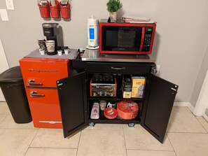 Kitchenette equipped with a refrigerator, coffee maker, and microwave, perfect for preparing a quick meal.