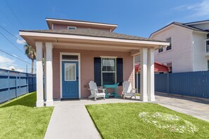 Einbungalow mit Veranda, einer blauen Tür und zwei weißen Stühlen.