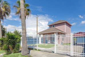 A fenced property with a single-story building, a clear sky, and palm trees.