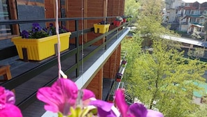 A balcony with yellow planters and flowers, overlooking a residential area with trees and houses. - Hotel Ireland (Manali)