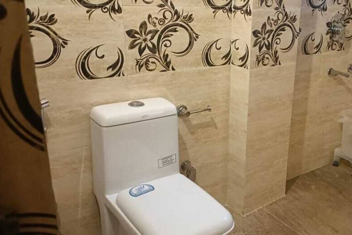 A bathroom with a toilet, a bidet, and a wall with a floral pattern.