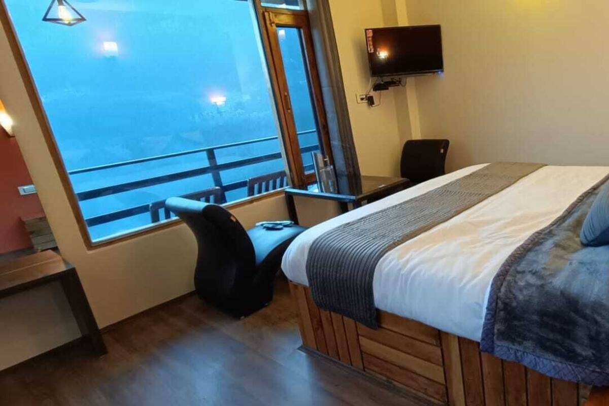A hotel room with a bed, a desk, a chair, a TV, and a window with a view.