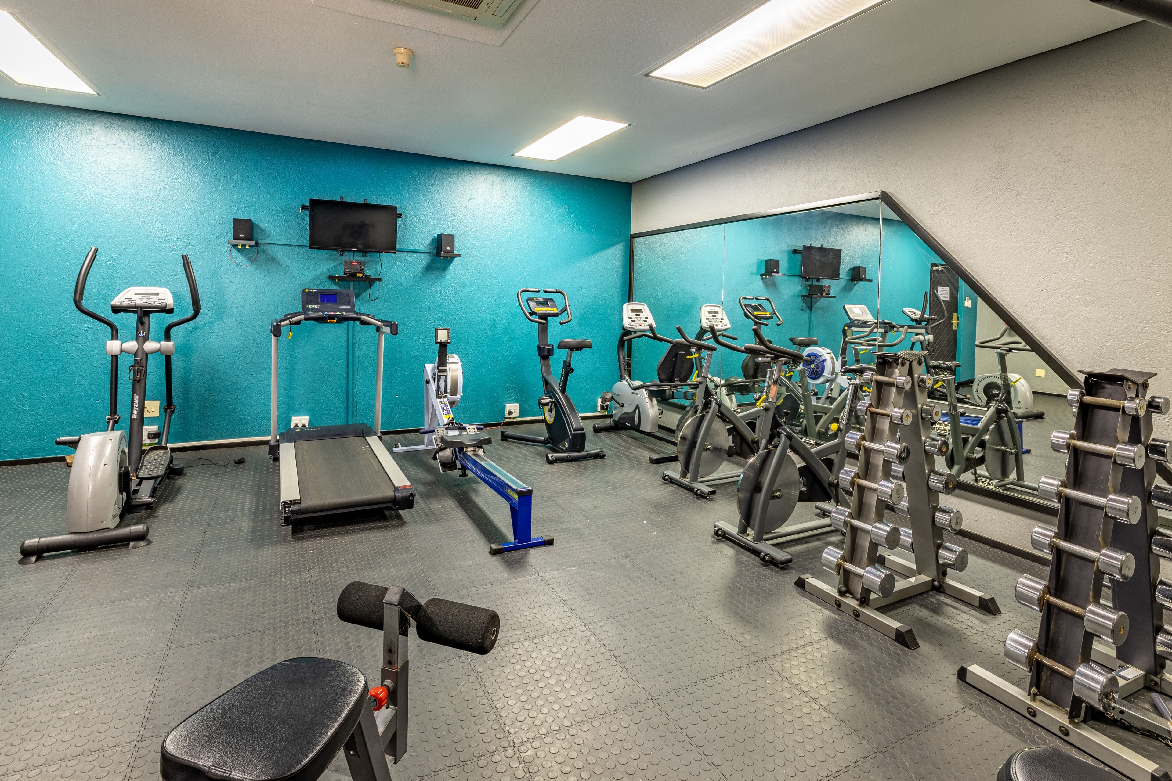 A gym with various exercise equipment, including treadmills, elliptical machines, and weightlifting stations.