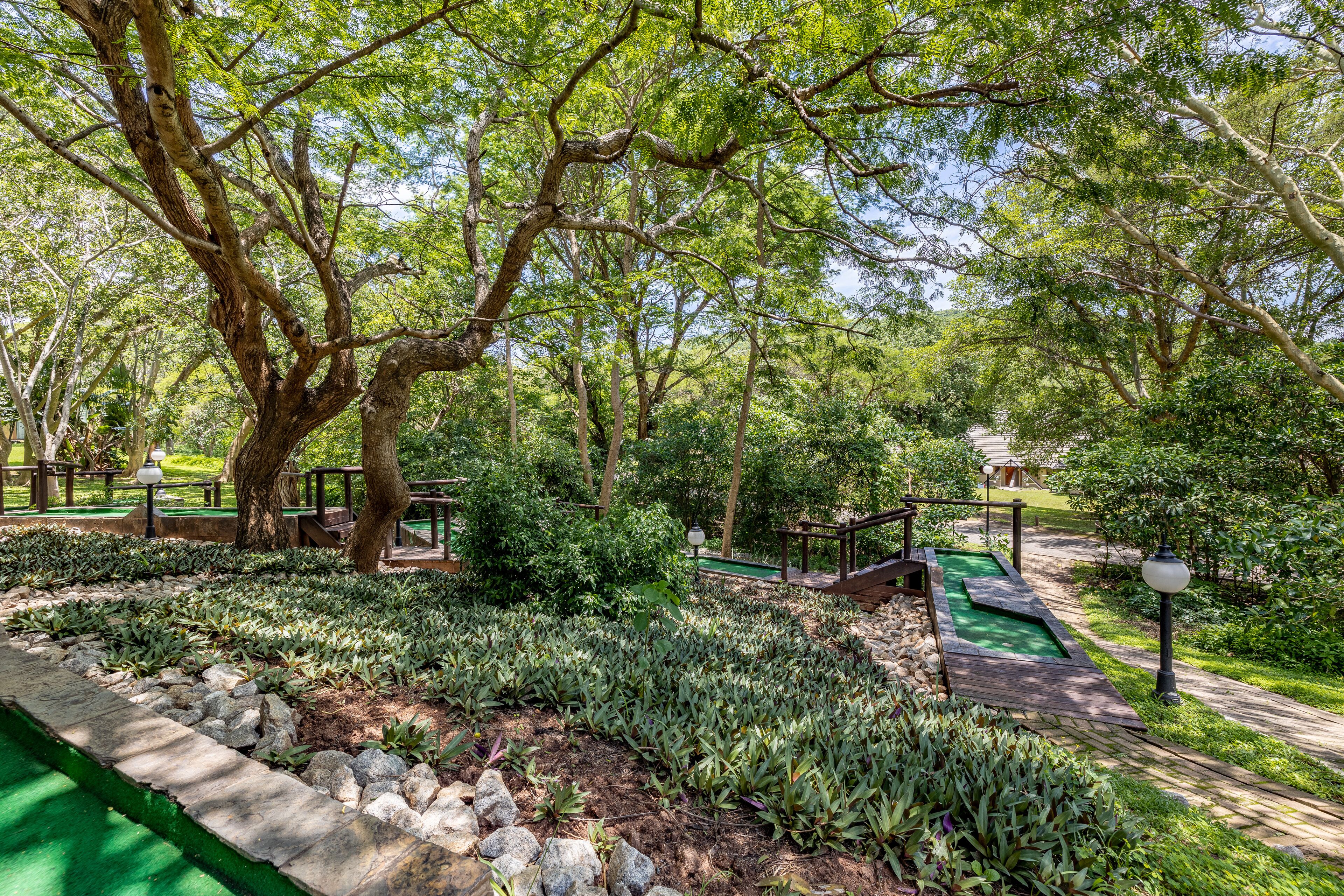 A landscaped garden with a wooden pathway, benches, and a small green play area.