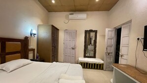 Une chambre d’hôtel avec un grand lit, une table de chevet, un miroir, une armoire et une salle de bain équipée d’un lavabo et de toilettes.