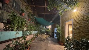 Une cour intérieure agrémentée de plantes en pot, d’un mur en briques et d’un espace aménagé pour s’asseoir.