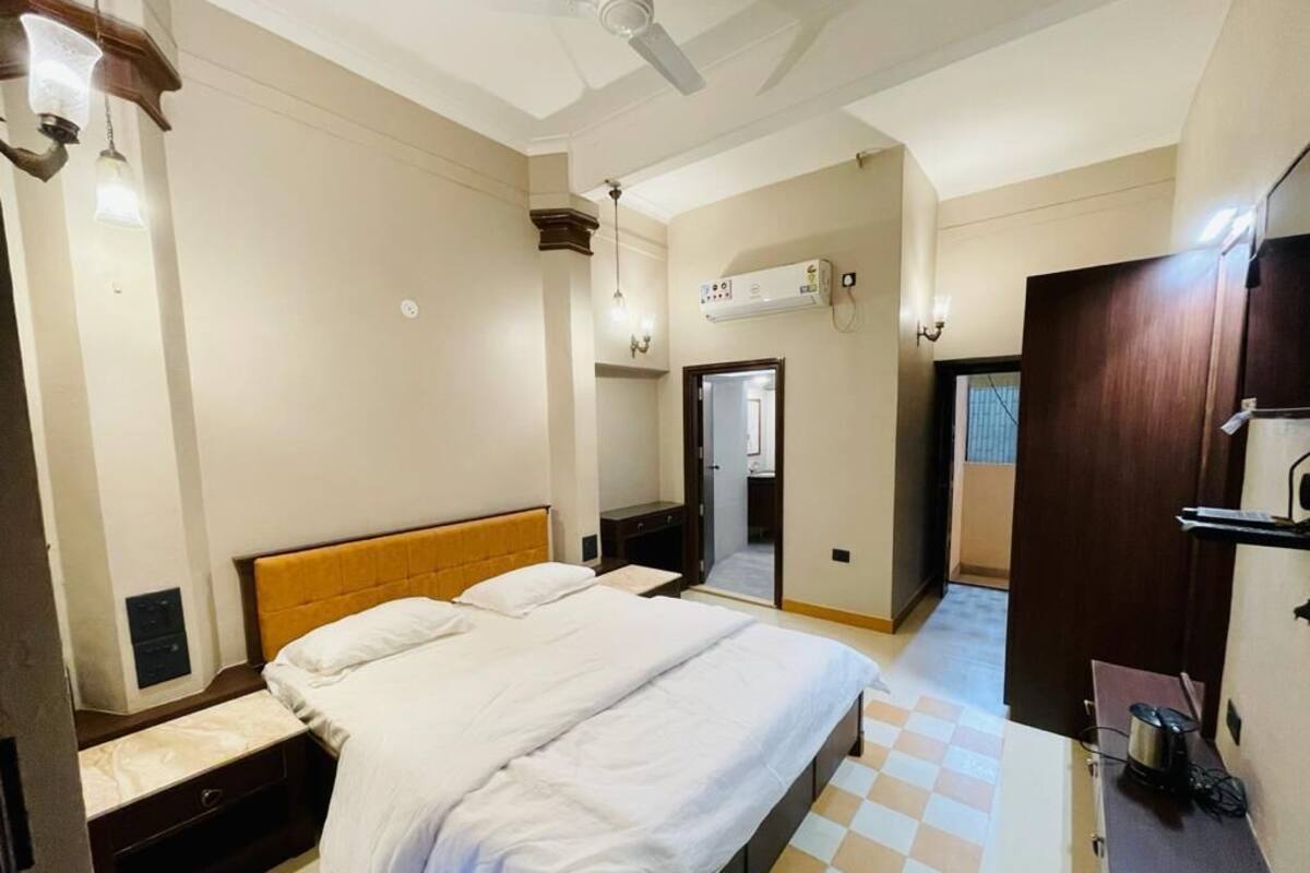 Une chambre d’hôtel avec un grand lit, des tables de chevet, un ventilateur de plafond, un appareil de climatisation et un sol à carreaux.