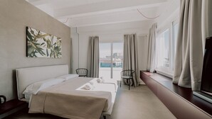 A modern hotel room with a large bed, a seating area by the window, and a city view. - Suite Donna Edwige by MONHOLIDAY (Monopoli)