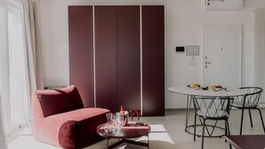 A modern living room with a red sofa, a round dining table with chairs, and a large wardrobe. - Suite Donna Edwige by MONHOLIDAY (Monopoli)