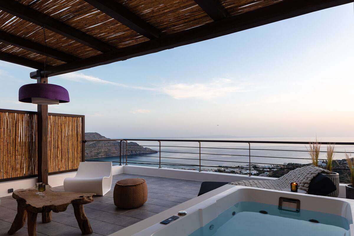 A rooftop terrace with a hot tub, seating area, and a view of the sea.