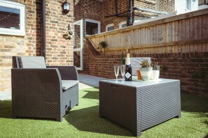 A patio with wicker furniture, a bottle of champagne, and potted plants.