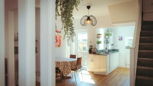 Una cucina moderna con isola centrale, zona pranzo con tovaglia fantasia e una scala che conduce a un altro livello.