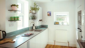 Una cucina moderna con mobili bianchi, un lavello in acciaio inossidabile e una finestra che fa entrare luce naturale.