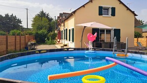 A swimming pool with inflatable toys, a patio area, and a house in the background. - Gîte** 13 beds, sleeps 20, Jacuzzi, Swimming pool, Billiards, Games tent, Park **. (Mohon)