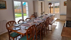A dining area with a long table set for six, wooden chairs, and pendant lighting. - Gîte** 13 beds, sleeps 20, Jacuzzi, Swimming pool, Billiards, Games tent, Park **. (Mohon)