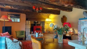 A cozy living room with a fireplace, a dining table, and comfortable seating. - Gîte** 13 beds, sleeps 20, Jacuzzi, Swimming pool, Billiards, Games tent, Park **. (Mohon)