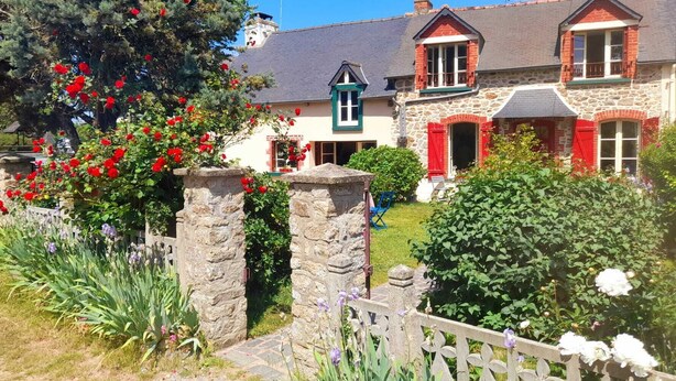 A stone house with red shutters, a stone gate, and a garden with red flowers. - Gîte** 13 beds, sleeps 20, Jacuzzi, Swimming pool, Billiards, Games tent, Park **. (Mohon)