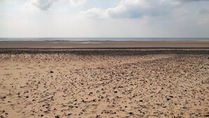 Una playa con un primer plano rocoso y una amplia zona arenosa.