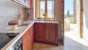 Una cocina con armarios de madera, horno empotrado y ventana con vistas al exterior.