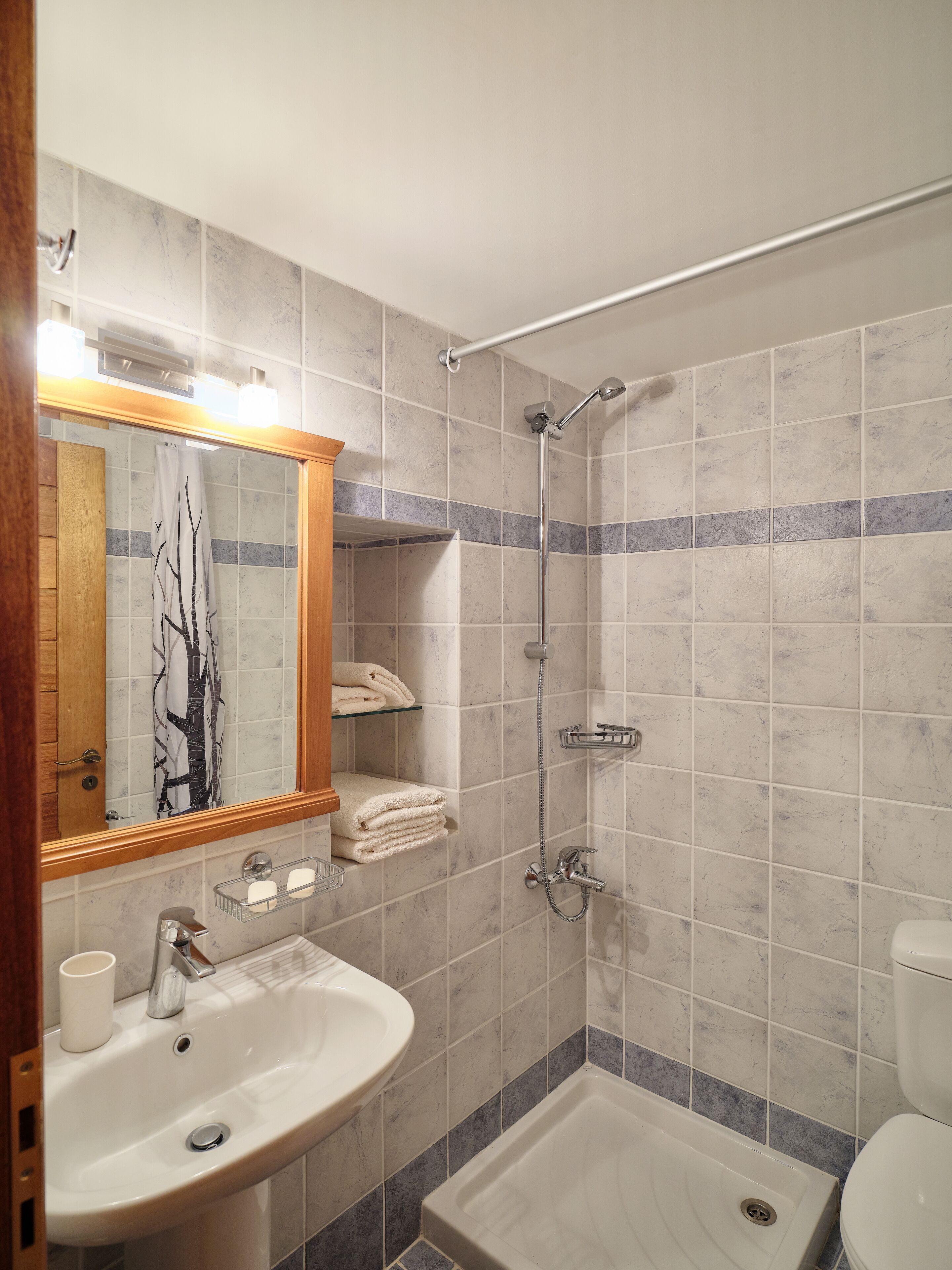 A bathroom with a sink, mirror, shower, and toilet.
