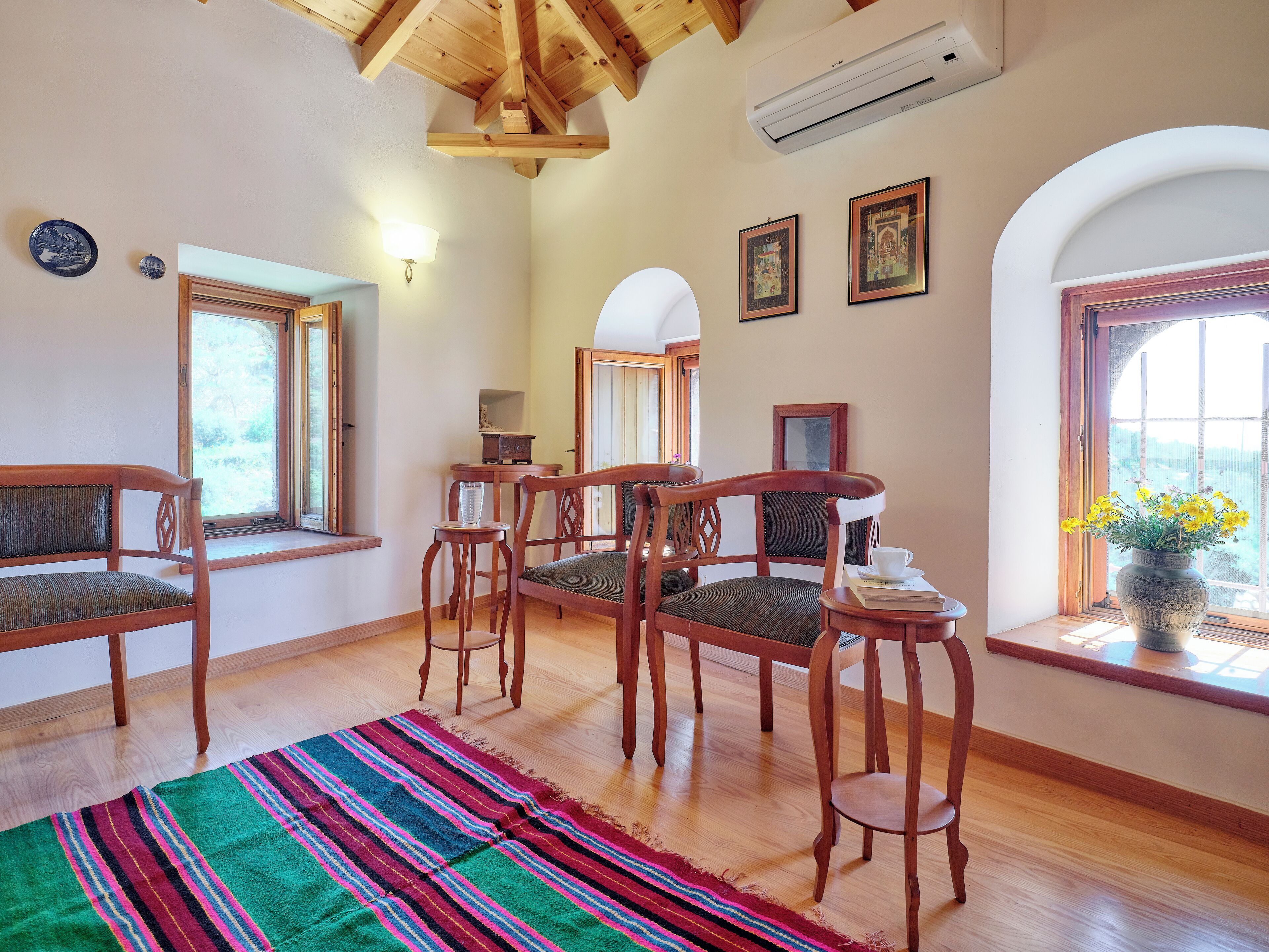 A cozy room with wooden furniture, a colorful rug, and a window with a view.