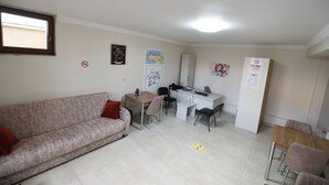 A small, well-lit room with a sofa, a dining table, and a kitchenette. - Trigo Hotel (Nevsehir)