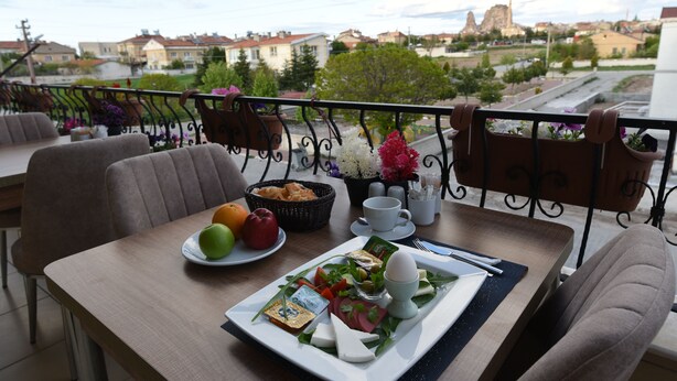 A balcony with a table set for breakfast, including eggs, cheese, and fruits. - Trigo Hotel (Nevsehir)
