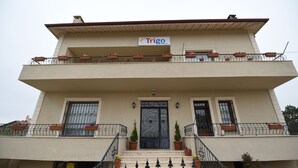 A two-story building with a balcony on the upper floor, a sign reading "Trigo Hotel" above the entrance, and potted plants on the balcony railings. - Trigo Hotel (Nevsehir)