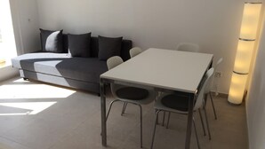 A modern living room with a grey sofa, a white dining table, and two chairs. - CENTRAL AND RENOVATED APARTMENT, 100m FROM THE BEACH (Torroella de Montgrí)