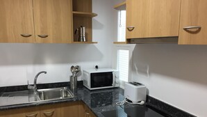 A kitchen with wooden cabinets, a stainless steel sink, a microwave, a toaster, and a coffee maker. - CENTRAL AND RENOVATED APARTMENT, 100m FROM THE BEACH (Torroella de Montgrí)