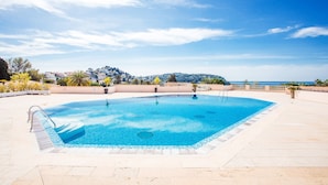 Una piscina rectangular con superficie de agua azul cristalina, rodeada por una solana con baldosas.