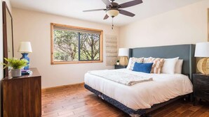 A bedroom with a bed, a ceiling fan, a window, and a dresser.