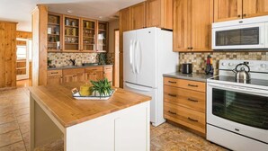 A kitchen with wooden cabinets, a white refrigerator, a microwave, and an oven.