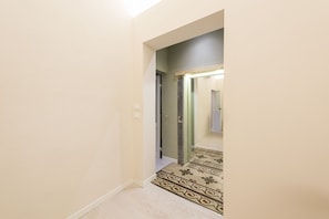 Leading to a room, this hallway features a geometric-patterned carpet and light-colored walls.