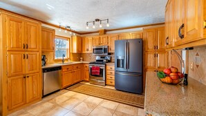 A kitchen with wooden cabinets, stainless steel appliances, a microwave, a refrigerator, and a fruit basket on the counter. - Hot Tub in 39 Acres of Aspens - Mtn Views, 23mi to Breck, Pet-Friendly (Fairplay)