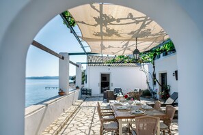 Un área de comedor al aire libre con una mesa para cuatro, con vistas a un cuerpo de agua.