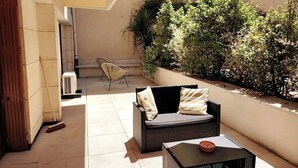 Ein Patio mit einem Korbsessel, einem kleinen Tisch und einem Stuhl.
